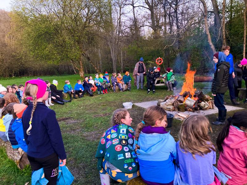 Young people sitting in a circle round a campfire at camp.